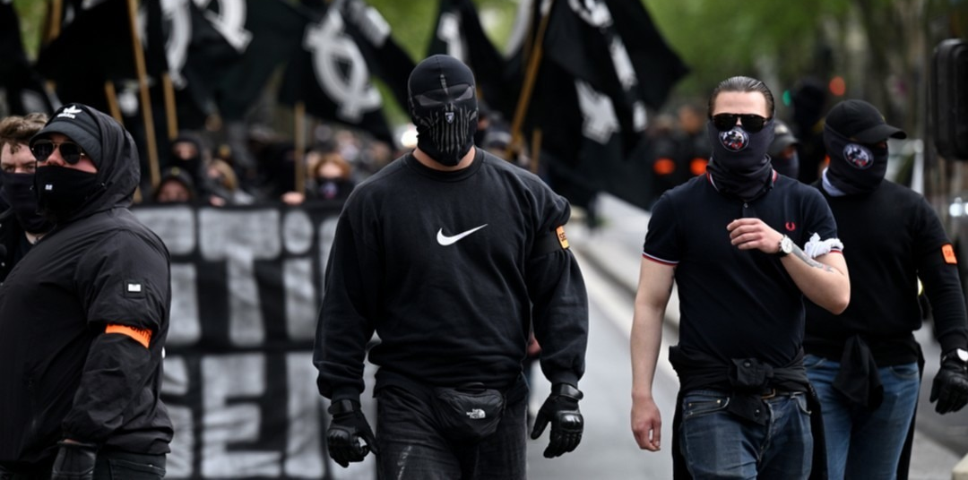 Demonstrators dressed in black, wearing masks and carrying black flags